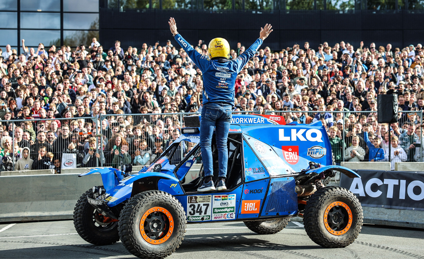Coureur en auto voor een volle tribune tijdens een live demonstratie